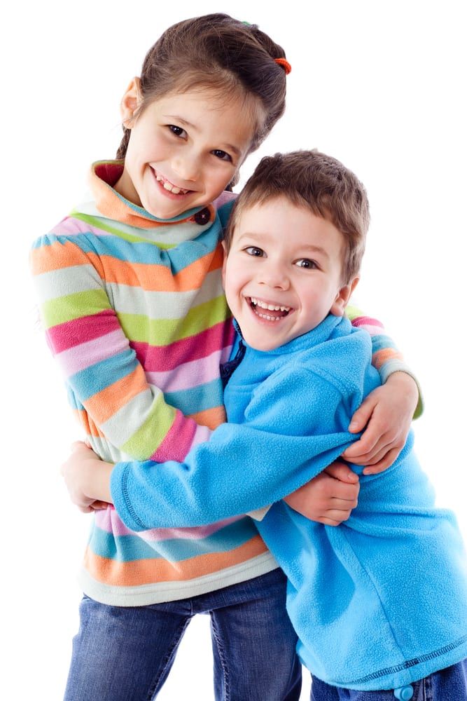 Two kids around 5-6 year old hugging each other and smiling